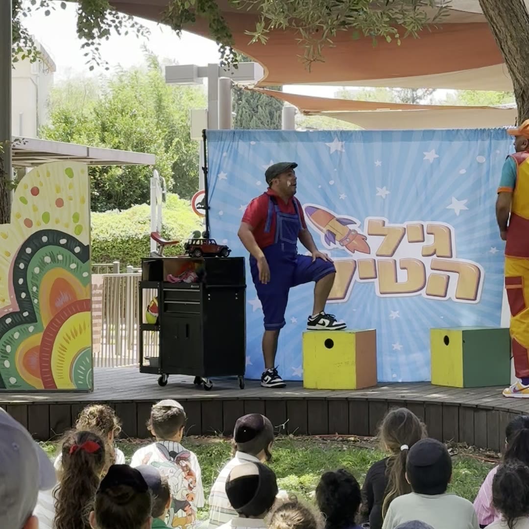 קהל ילדים יושב מרותק מול הבמה של גיל הטיל